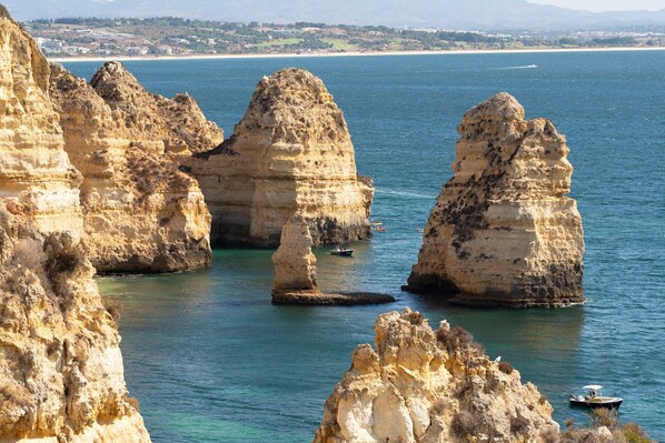 A coastal landscape with prominent rock formations and clear blue water.