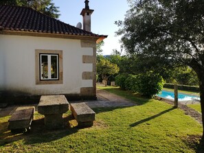 A house with a tiled roof, a small window, and a stone bench in the yard. - CHARMING HOUSE Small Stone House (Queijada)