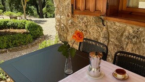 Ein Tisch mit Blumen in einer Vase, einer Kaffeetasse und einem Stuhl in einer Umgebung mit Steinwänden.
