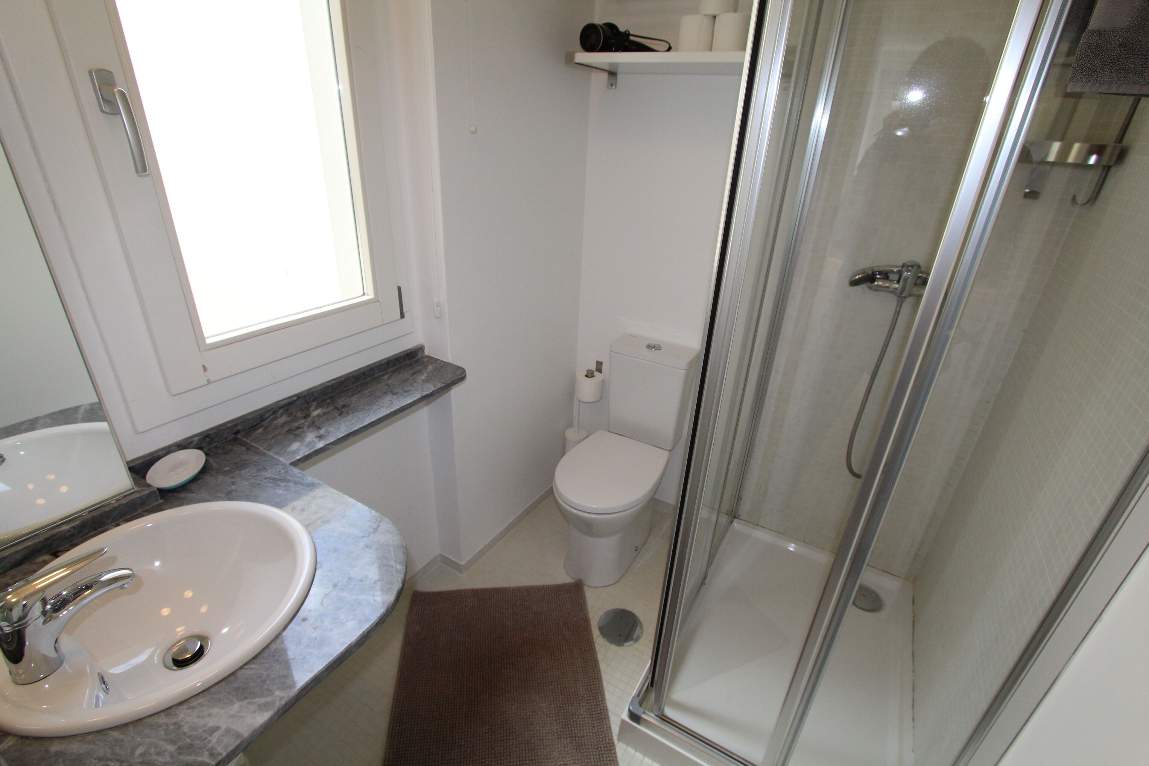 A bathroom with a sink, toilet, and glass-enclosed shower.