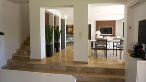 Ein modernes Interieur mit einer Treppe, die zu einem Essbereich, einer Küche und einem Wohnraum führt.