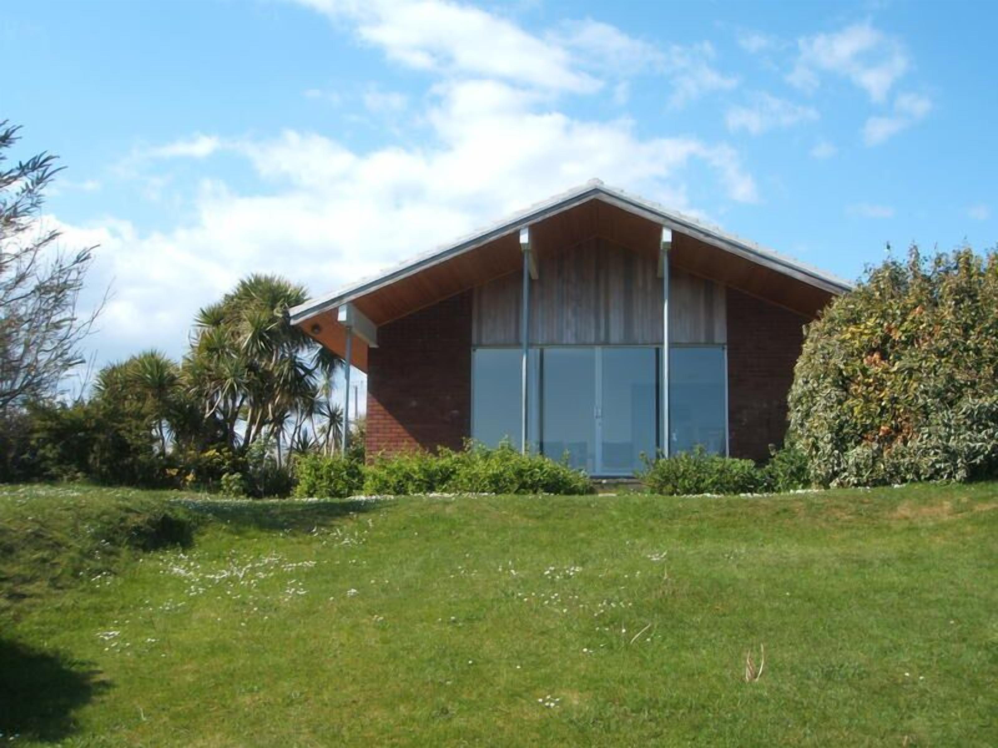 A single-story house with a sloped roof, large windows, and a brick exterior.