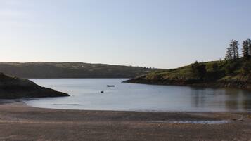 A calm lake with a boat, surrounded by grassy hills and a clear sky.