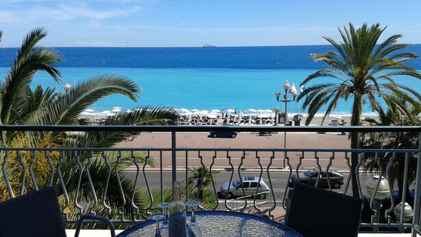 Ein Balkon mit Blick auf den Ozean, Palmen und Strandstühle.