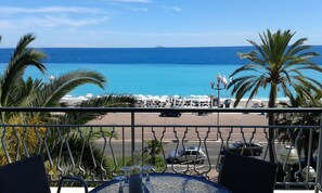 Un balcon avec vue sur l’océan, les palmiers et les parasols de plage.