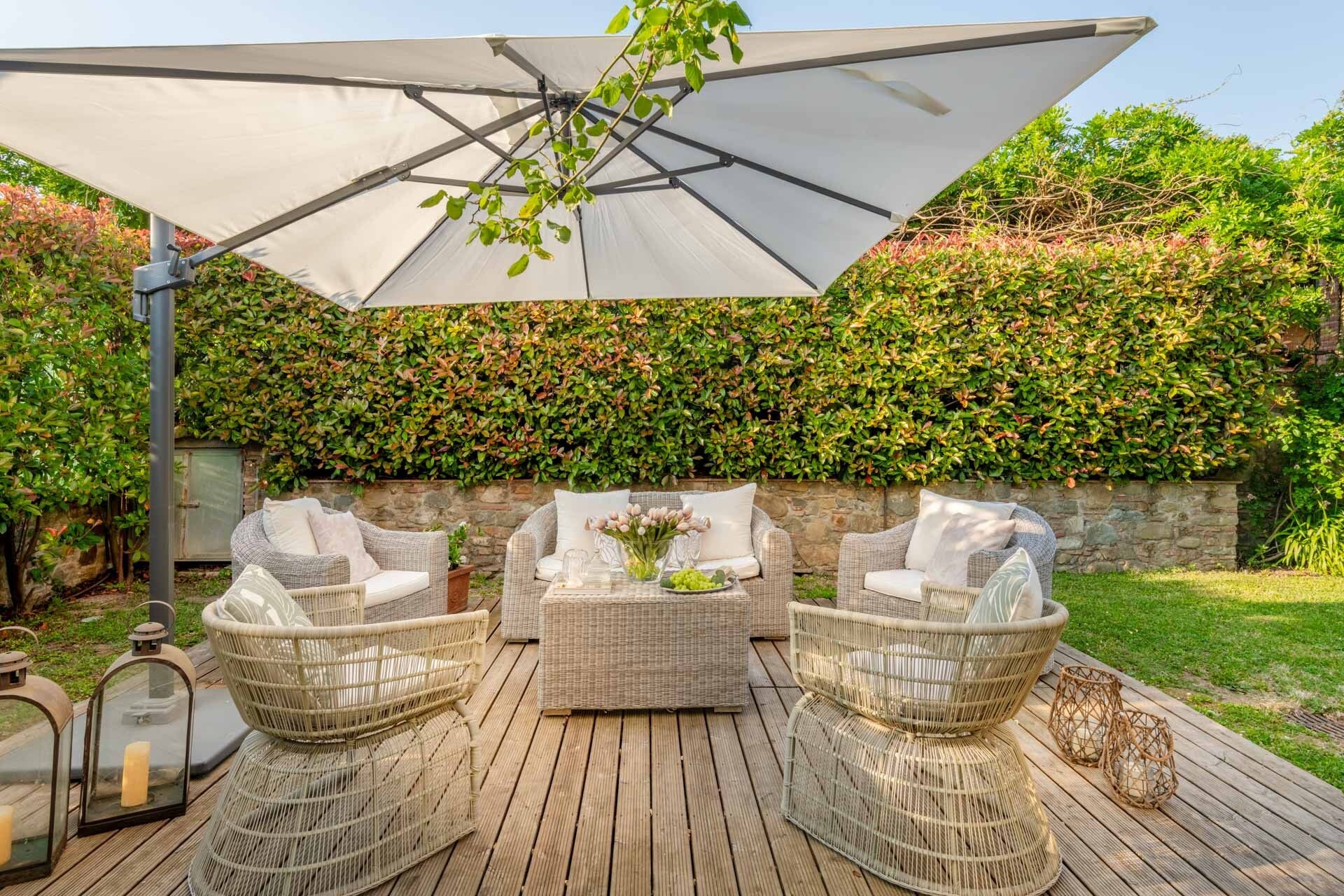 Zona exterior amb mobiliari de vimet, un parasol gran i una paret de vegetació.