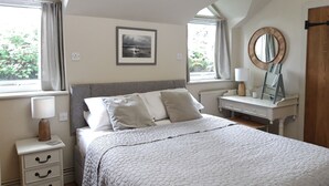 A bedroom with a bed, bedside table, dresser, and a window with curtains. - Stunning views of Snowdonia Mountains (Near Caernarfon)