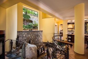 A staircase with a stone wall, a view of greenery, and a dining area with a lamp. - Villa Turtle with sea view and private pool (Massa Lubrense)