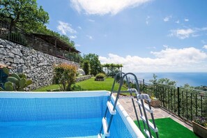 A swimming pool with a stone wall and a view of the sea. - Villa Turtle with sea view and private pool (Massa Lubrense)