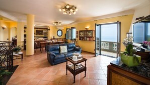 A living room with a sofa, coffee table, and a view of the sea through a glass door. - Villa Turtle with sea view and  private pool (Massa Lubrense)