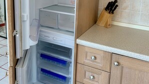An open refrigerator with multiple shelves and drawers, a kitchen counter with a knife block, and wooden cabinets. - Apartment with wonderful terrace on the sea - Finale Ligure (Finale Ligure)