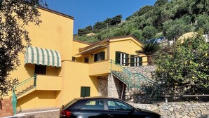 A black car parked in front of a yellow building with a stone staircase and a green awning. - Apartment with wonderful terrace on the sea - Finale Ligure (Finale Ligure)