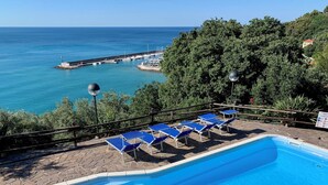 A swimming pool with blue chairs and a stone deck, overlooking a marina and the sea. - Apartment with wonderful terrace on the sea - Finale Ligure (Finale Ligure)