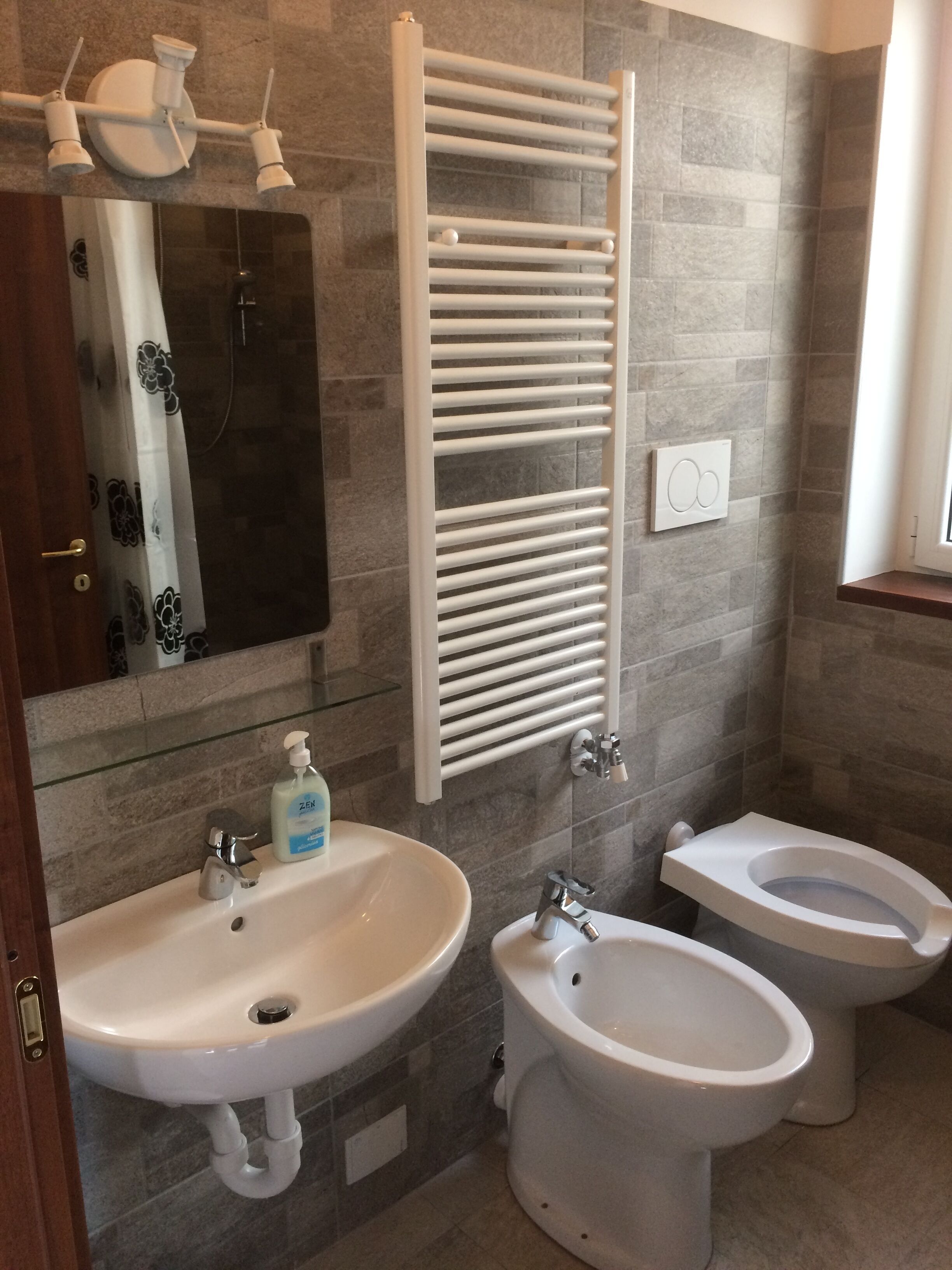 Une salle de bain avec deux lavabos, des toilettes, un porte-serviettes et une douche.