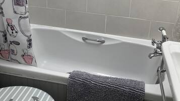 Een bad/douchecombinatie, een haardroger, handdoeken, zeep