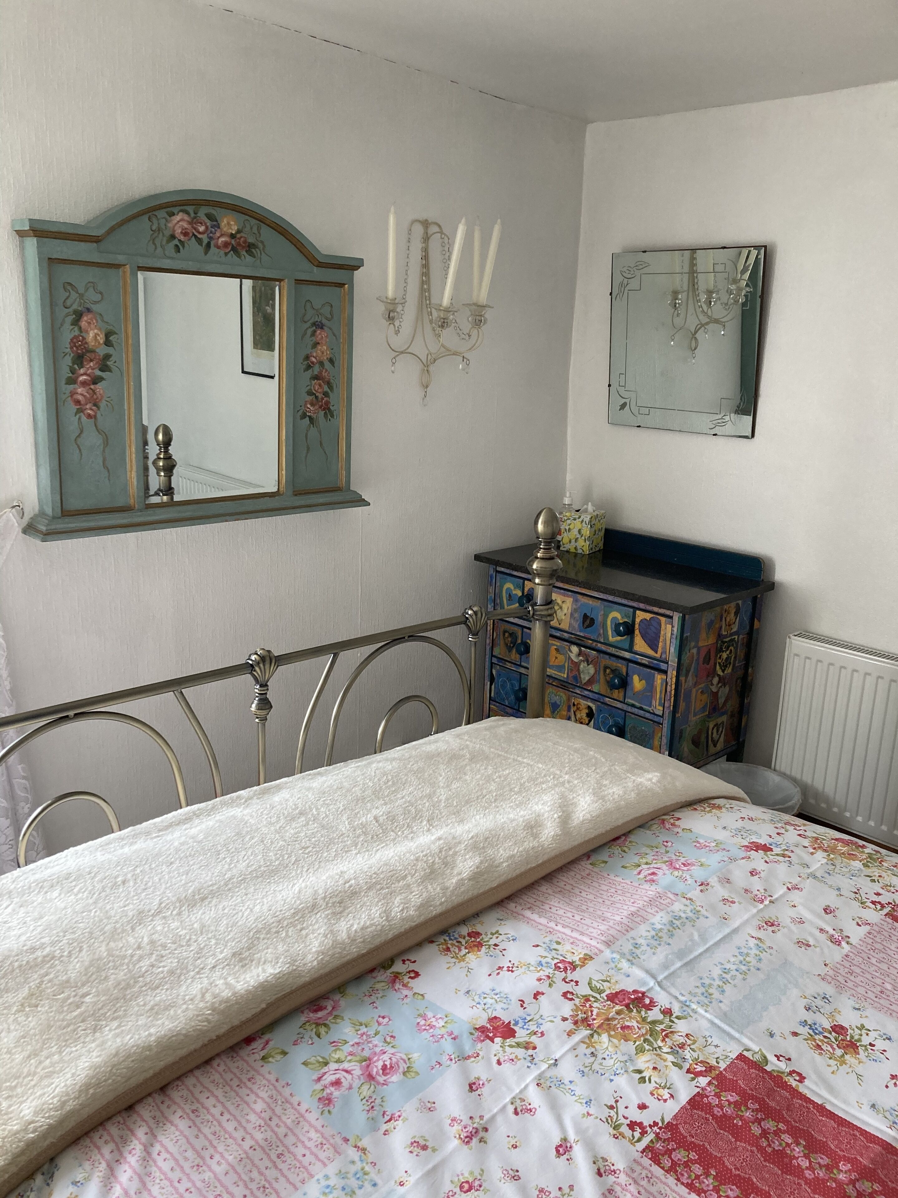 A bedroom with a bed, a dresser, a mirror, and a radiator.