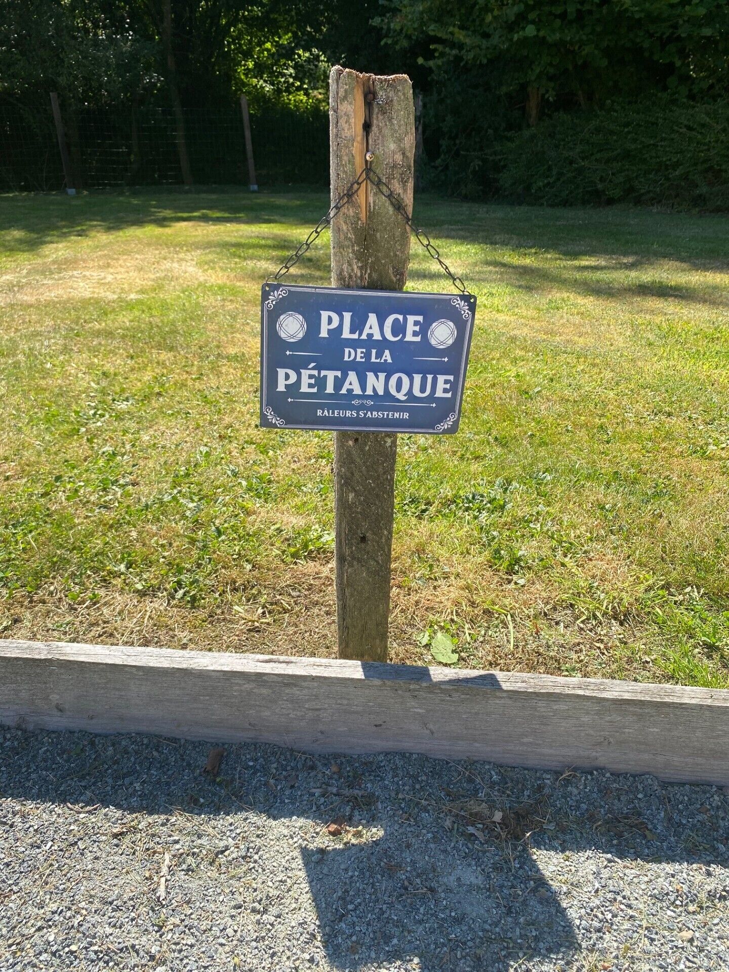 A sign on a wooden post with a message in French.