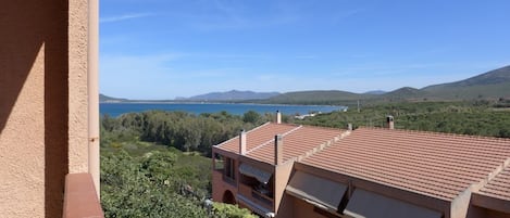 A balcony with a view of a coastal landscape, including a body of water and distant hills.