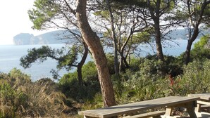 Ein Holztisch für ein Picknick in einer natürlichen Umgebung mit Bäumen und Blick aufs Meer.