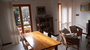 Ein Essbereich mit einem Holztisch und Stühlen, einem Schrank mit Geschirr und einem Fenster mit Vorhängen.