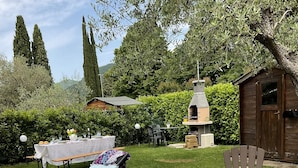 An outdoor patio area with a table set for a meal, a lounge chair, and a barbecue grill.