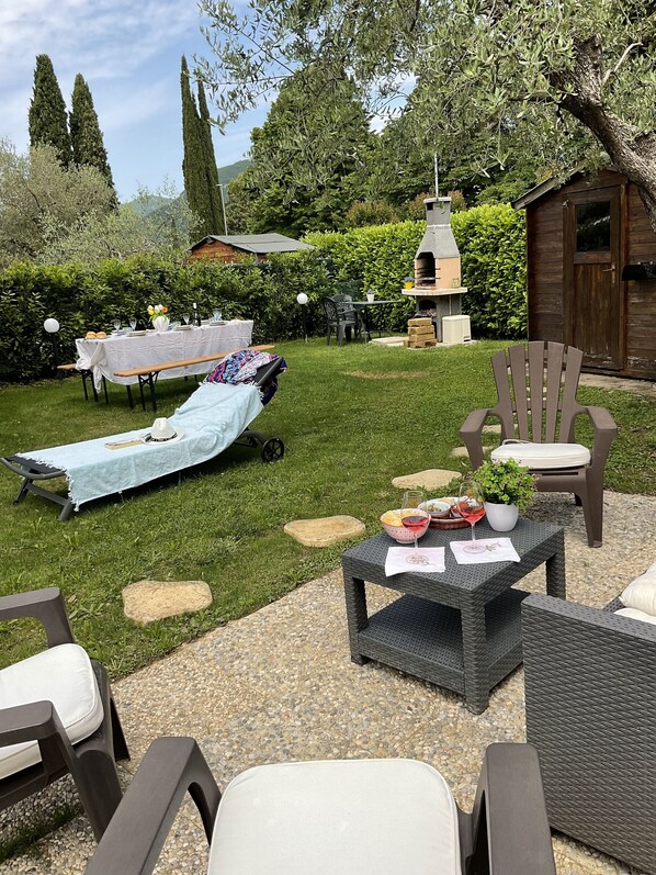 Un área de patio al aire libre con una mesa lista para comer, una silla de descanso y una parrilla.