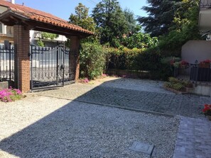 A paved driveway leading to a gated entrance with a brick structure and a metal gate.