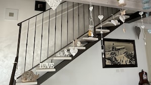 A staircase with a 'LOVE' sign, heart-shaped decorations, and a vintage photograph on the wall.