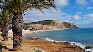 A beach with palm trees, a rocky shoreline, and a cliff in the background. - WAKE UP TO THE SOUND OF THE SEA T1 CENTRAL-AIR CONDITIONING(FREE WIFI) 3' BEACH (Luz)