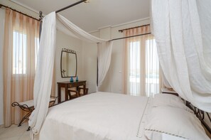 Une chambre à coucher avec un lit à baldaquin, une table de chevet, un miroir et des rideaux en voile.