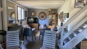 Ein großzügiger Wohnbereich mit Treppe, Fernseher und Esstisch.