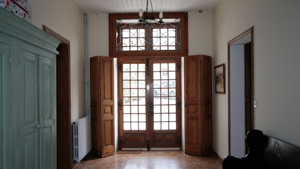 Un pasillo con una puerta de madera, un radiador y un banco.