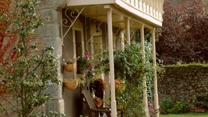 Un bâtiment en pierre doté d’un balcon, de paniers en osier et de plantes en pot.