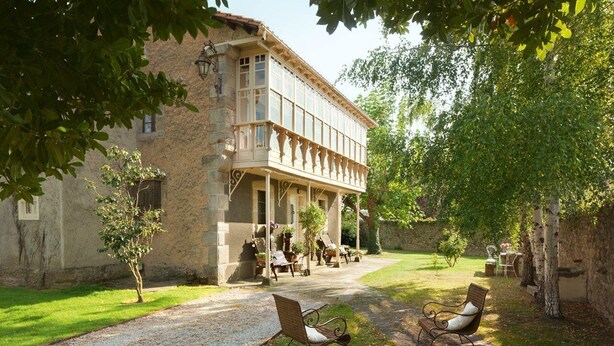 Un bâtiment doté d’un balcon, d’un chemin de gravier et d’un espace extérieur aménagé pour s’asseoir.