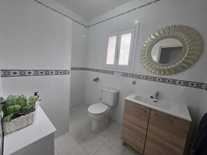 A bathroom with white tiles, a toilet, a sink, and a mirror. - Villa 4 bed/bath with free heated pool ,WiFi and TV Car not essential (Mijas)