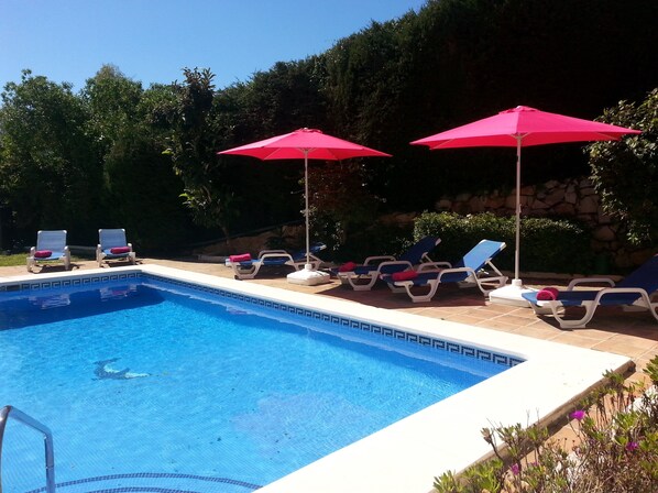A swimming pool with lounge chairs and red umbrellas. - Villa 4 bed/bath with free heated pool ,WiFi and TV Car not essential (Mijas)