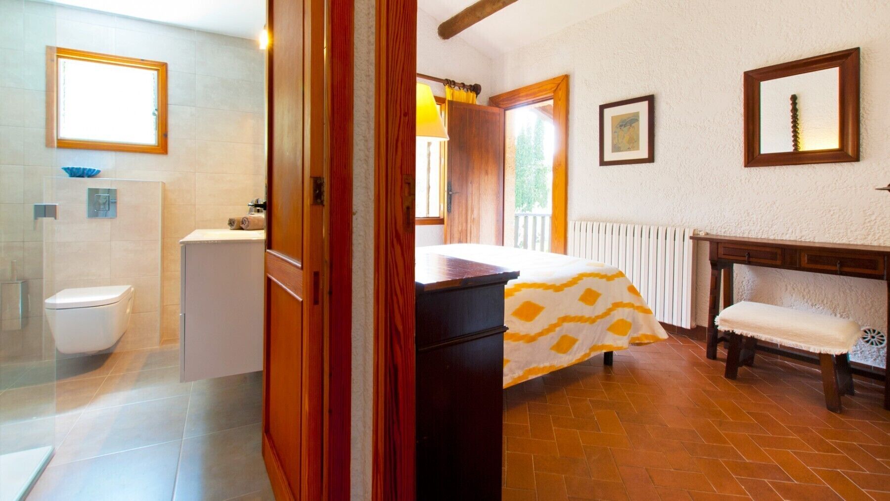 A bathroom with a toilet, a sink, and a shower. There is a wooden door leading to another room.