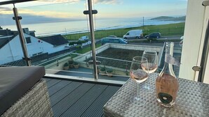 Un balcone con mobili in vimini, una bottiglia di vino e dei bicchieri.