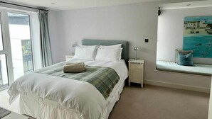 Una camera spaziosa con un letto grande, un comodino, una panca finestrata e un quadro.