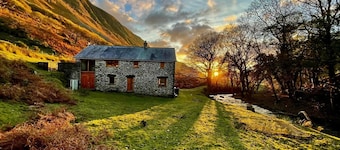 Konverterte vannmølle med vakker elv og majestetiske fjell på dørstokken