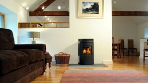 Una sala de estar acogedora con chimenea, vigas de madera, un sofá y una zona de comedor.