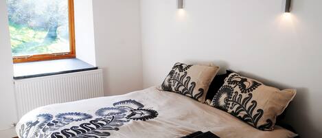 A bedroom with a bed, a window, and a radiator.