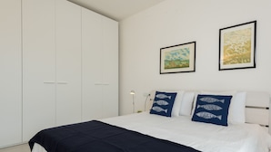 Une chambre à coucher avec un lit, une armoire blanche et deux tableaux encadrés accrochés au mur.
