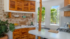 A kitchen with wooden cabinets, a stone wall, and a view of palm trees. - Villa CASA VERDE with private parking and swimming pool. WIFI, A/C, Terraces and BBCOA⭐⭐⭐⭐⭐ (sant francesc)