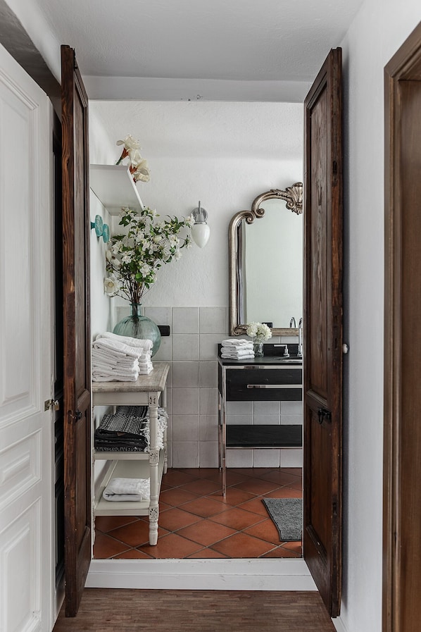 A bathroom with a white vanity, a mirror, a sink, and a towel rack.