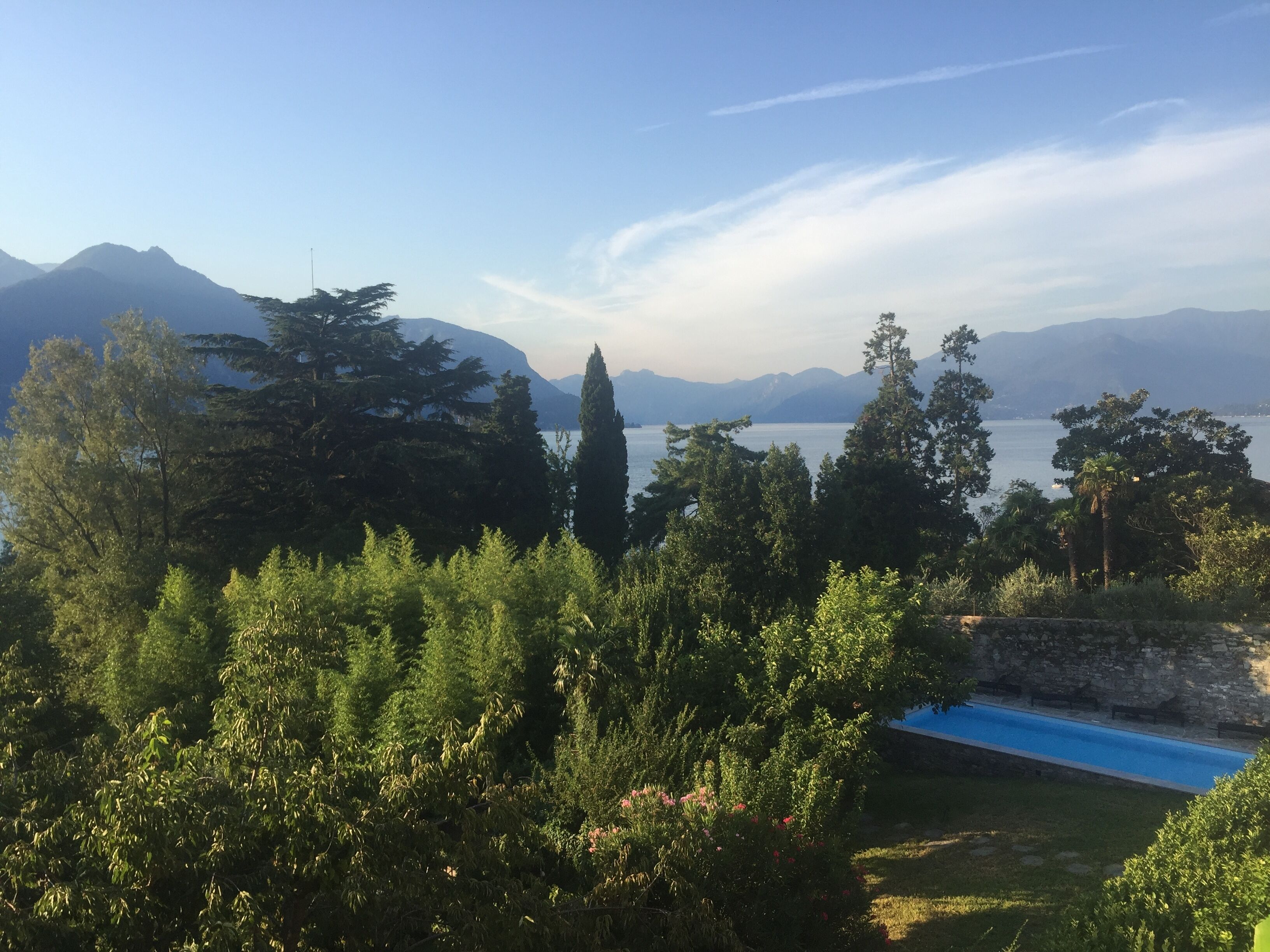A view of a mountainous landscape with a clear sky, a body of water, and a swimming pool.
