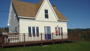 A two-story house with a gabled roof, a front porch, and a flag. - Home from Home -  Cosy Cottage in Whale Watching Country (Little River)
