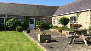 A stone building with a tiled roof, a grassy lawn, and a picnic table. - 3 Glantraeth Farm Cottage. Pet friendly, ideal base to explore Anglesey. (Trefdraeth, Bodorgan, Anglesey)