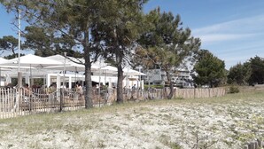 A beachside area with white tents, a wooden fence, and a building in the background. - Charming apartment on the 1st floor, St Goustan port of Auray. (Auray)