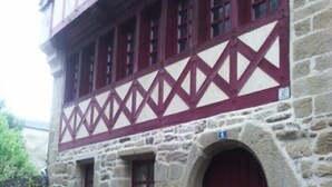 A stone building with a traditional half-timbered facade, featuring a large arched entrance and multiple windows with red frames. - Charming apartment on the 1st floor, St Goustan port of Auray. (Auray)